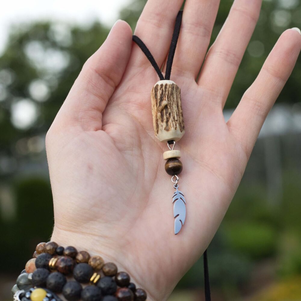 Handgemachte Halskette mit Anhänger aus Rotwildgeweih, Tigerauge-Perle, Holz und Edelstahlfeder an schwarzem Lederband.