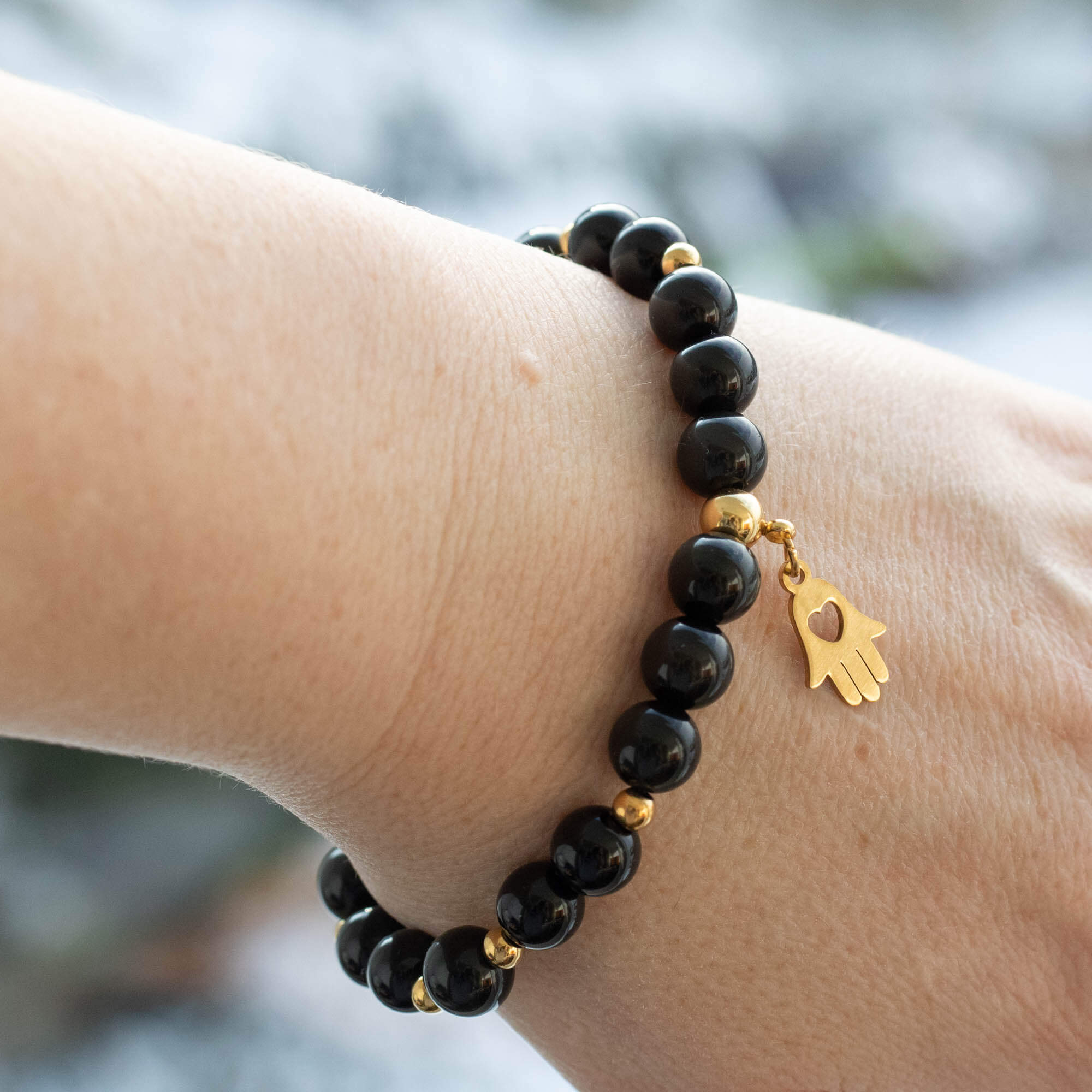 Black gemstone bracelet is made  with Obsidian and Agate beads combined with gold plated stainless steel spacers and Hamsa charm also call as Hand of Fatima.