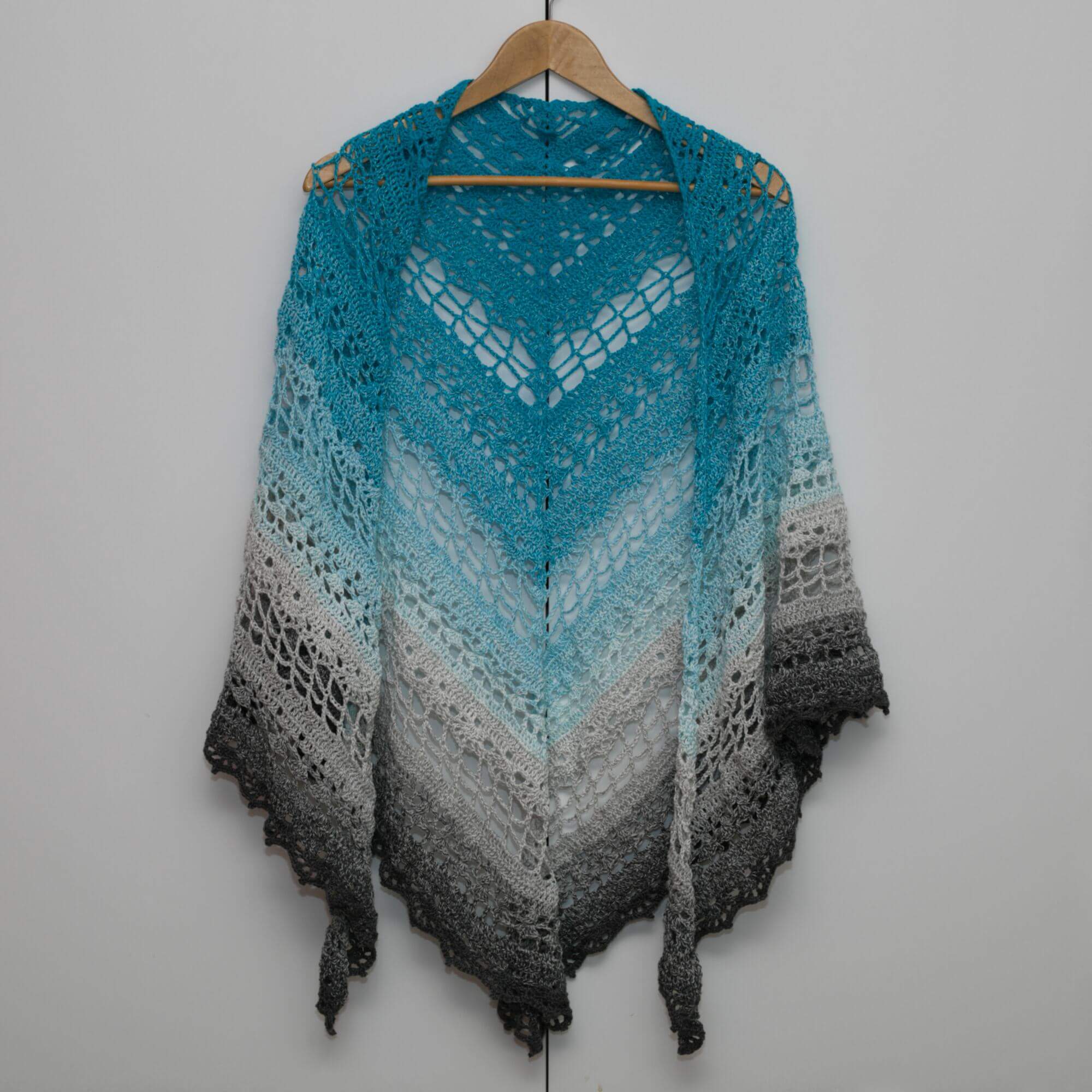 Handgefertigtes Dreieckshäkel-Tuch aus Ombre-Garn in Blau- und Grautönen, stilvoll, vielseitig und komfortabel für den Alltag.