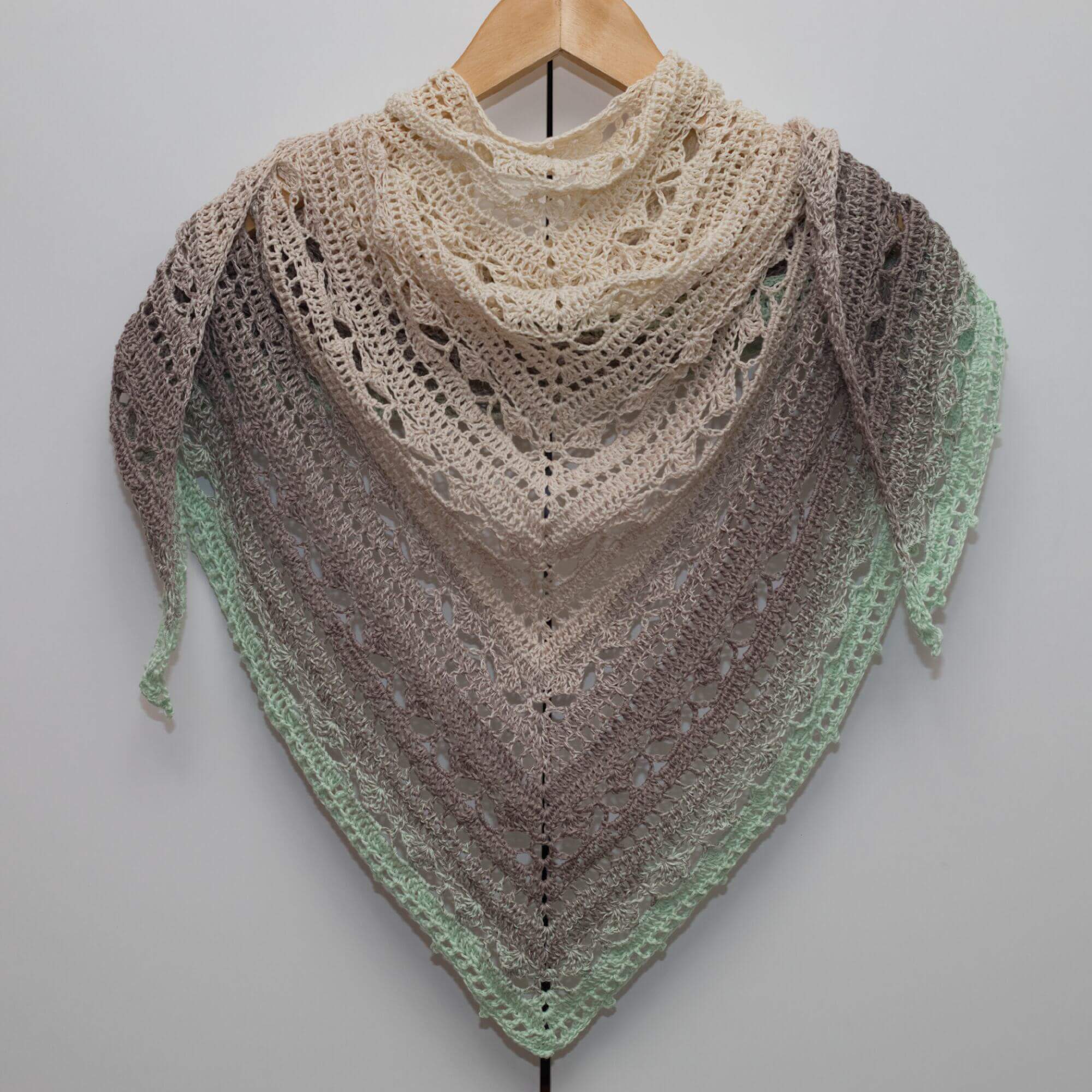 Handmade triangle crochet shawl created from high-quality yarn in pastel tones of cream, taupe, and pistachio green.