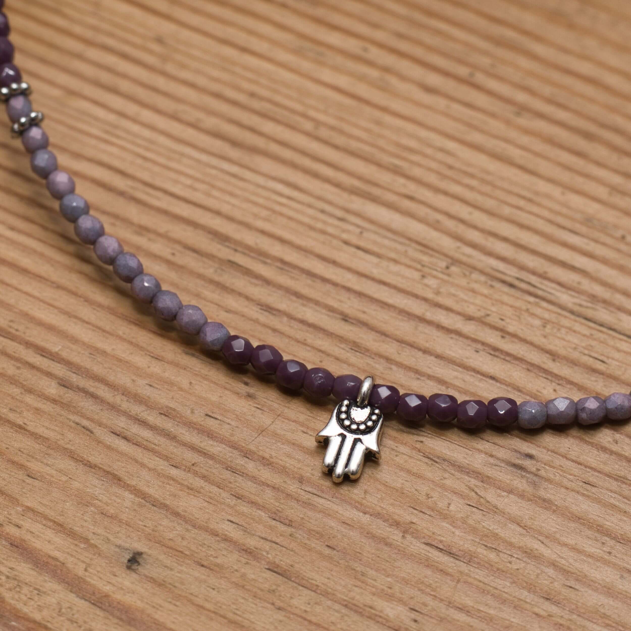 Handgefertigte Halskette mit violetten Glasperlen und Hamsa-Symbol für Schutz und Glück